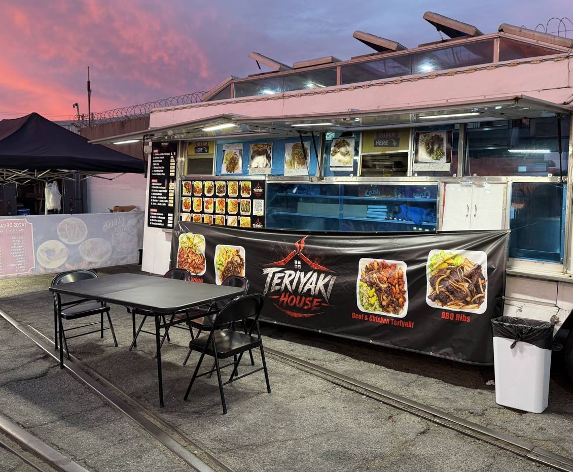 A food truck parked beside old rail tracks at sunset