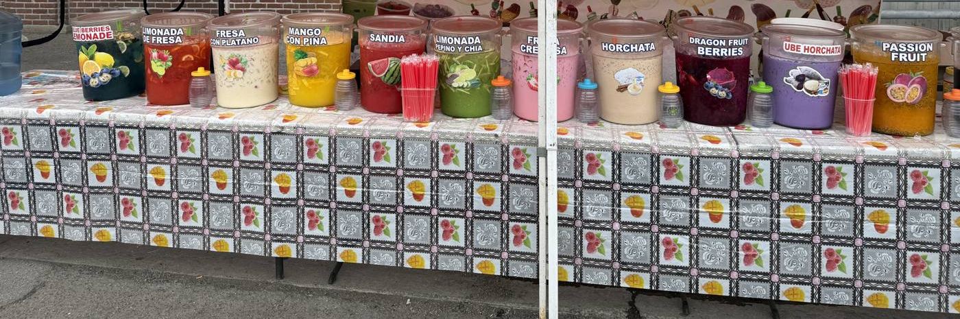 A table of large tubs of aguas frescas in many colors on a patterned tablecloth