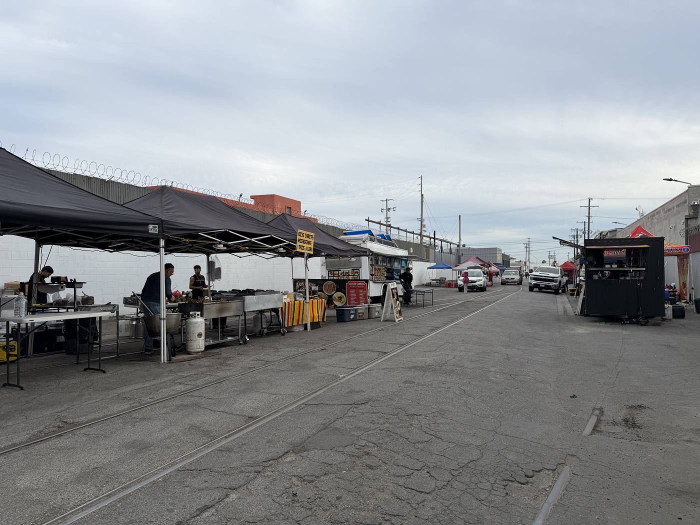 Grills under black canopies along the rail tracks in the market alley