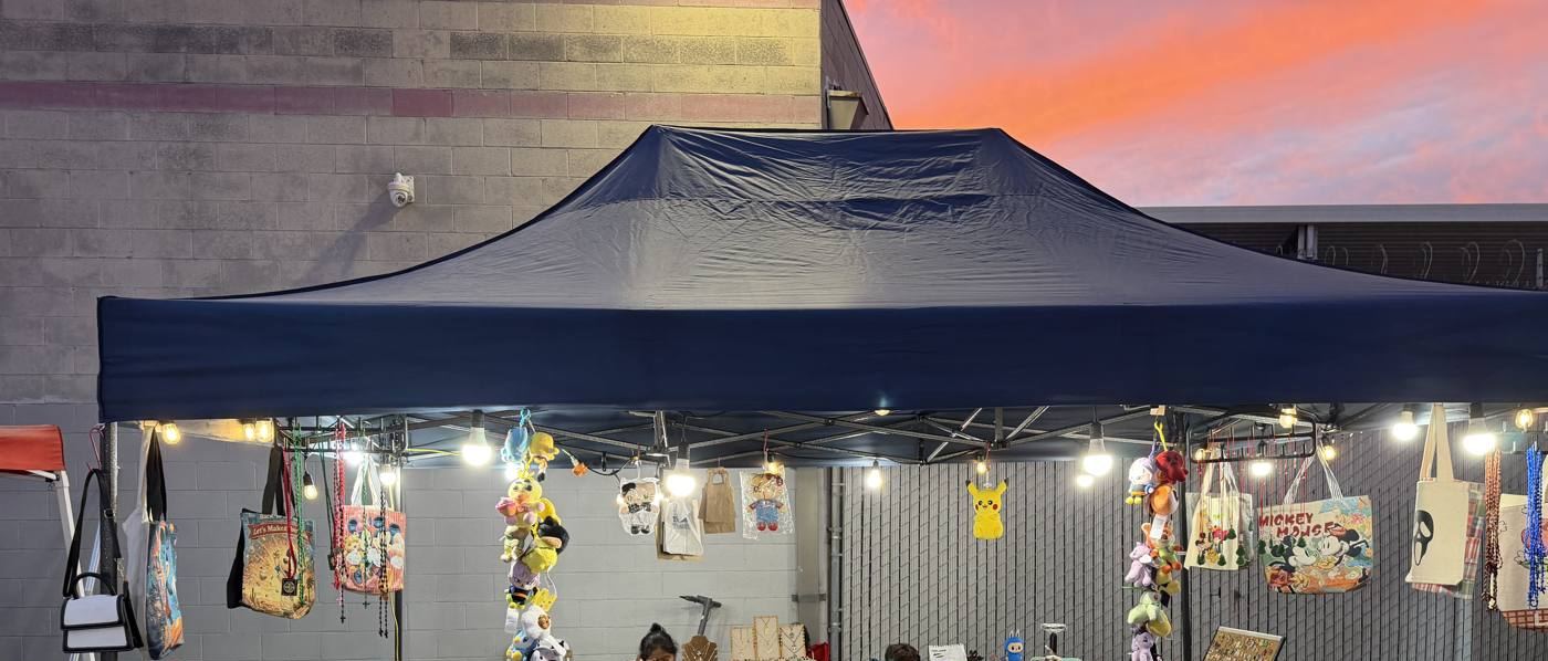 A merchandise tent hung with string lights, bags and plush toys
