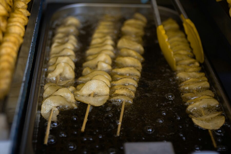 Brochetas de papa en espiral friéndose en aceite caliente