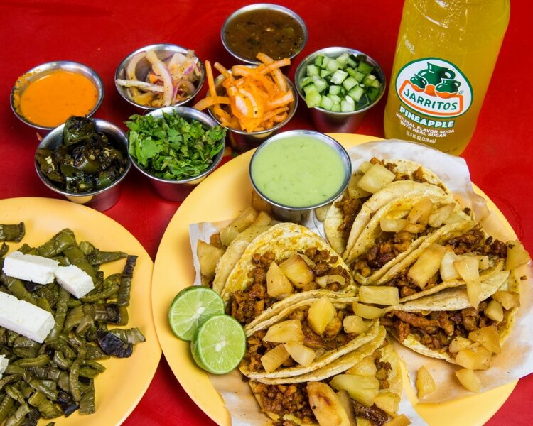 Tacos al pastor con limones, salsa verde y refresco Jarritos frío